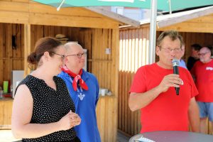 von links nach rechts, Lisa Gnadl, Rouven Kötter und Karl-Otto Waas begrüßen die Gäste, sommerlich gekleidet an Stehtischen, Karl-Otto Waas mit Mikrofon