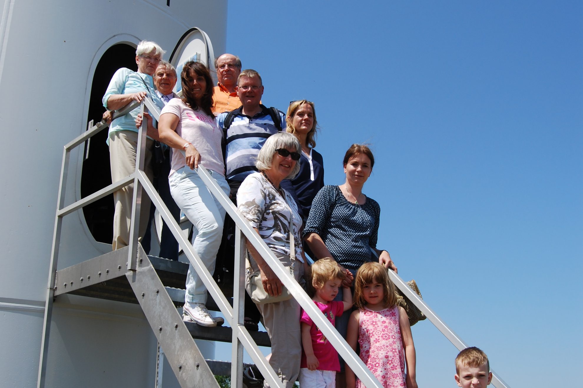 Besuchergruppe auf der Treppe vor dem Eingang einer der Anlagen in Kloppenheim bei sommerlichen Temperaturen.