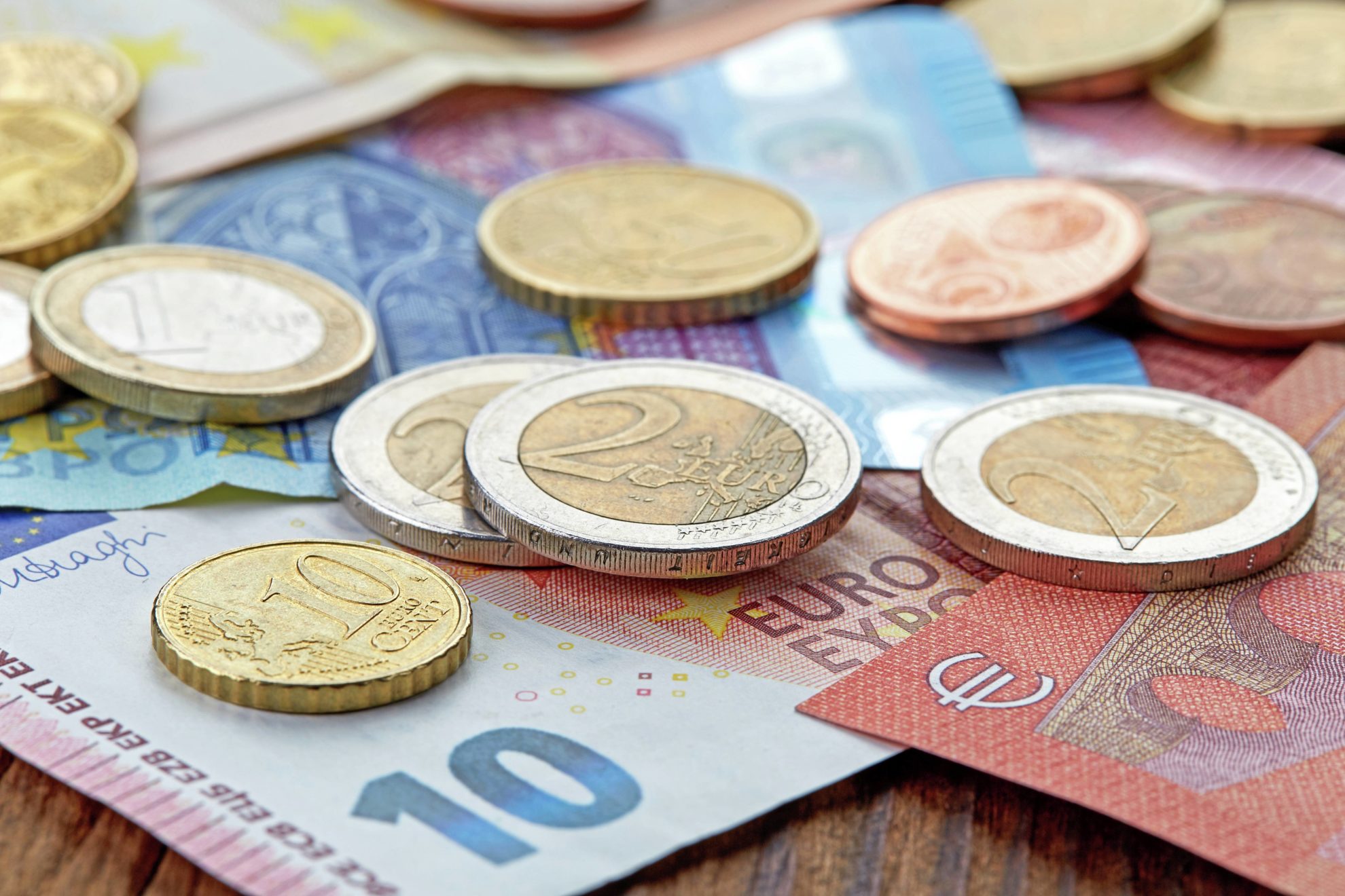 Banknoten und Münzen auf einem Holztisch als Illustration