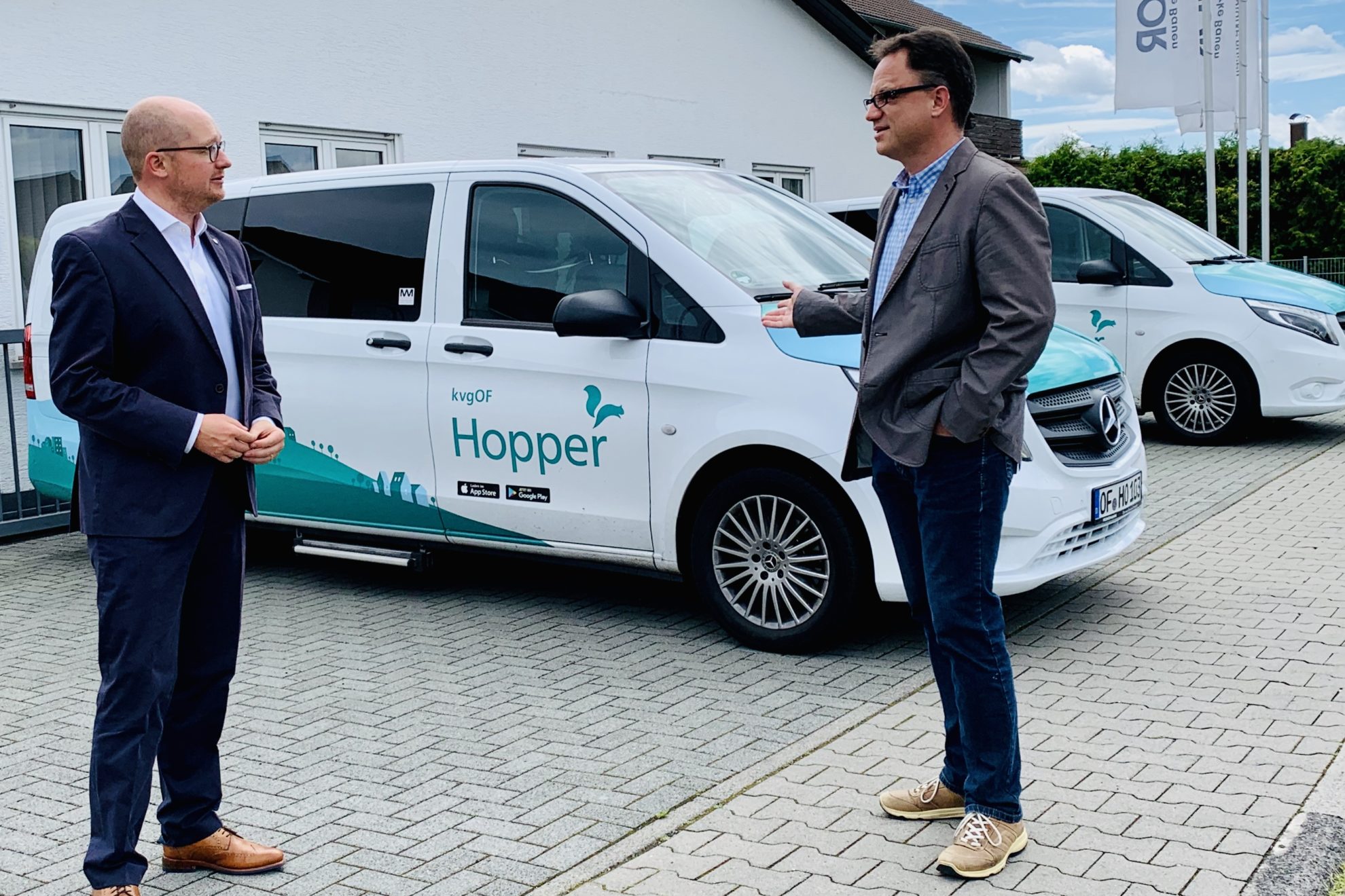 Rouven Kötter (links) bei der Hopper-Zentrale in Mainhausen mit dem dortigen Kreistagsabgeordneten Kai Gerfelder (SPD). Zwei Fahrzeuge der Hopper Flotte im Hintergrund